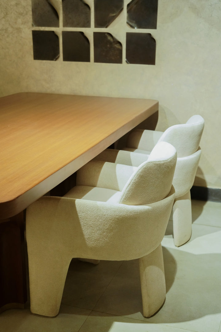 Wooden table with white chairs in a room with tiled walls.